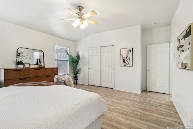 bedroom featuring lofted ceiling, a ceiling fan, baseboards, light wood-style floors, and a closet