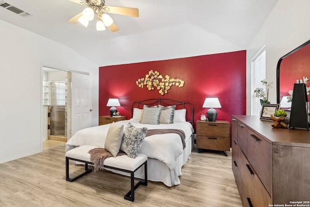 bedroom featuring lofted ceiling, an accent wall, light wood finished floors, and visible vents