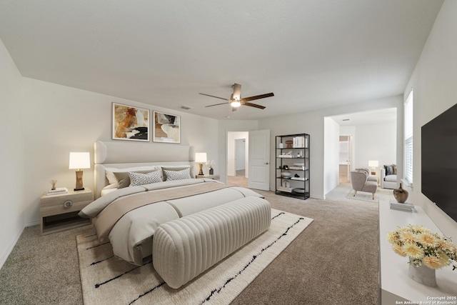 bedroom featuring visible vents, baseboards, light colored carpet, ceiling fan, and ensuite bathroom