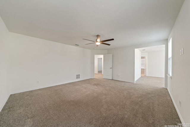 carpeted empty room featuring ceiling fan, visible vents, and baseboards