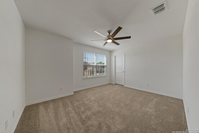 spare room featuring baseboards, ceiling fan, visible vents, and light colored carpet