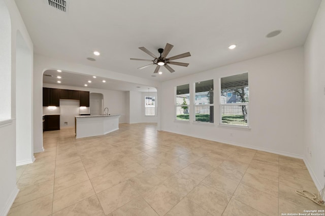 unfurnished living room featuring arched walkways, recessed lighting, visible vents, a sink, and ceiling fan