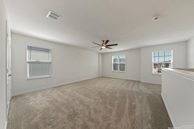 unfurnished room with baseboards, ceiling fan, visible vents, and light colored carpet