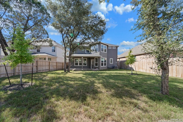 rear view of property featuring a yard and a fenced backyard