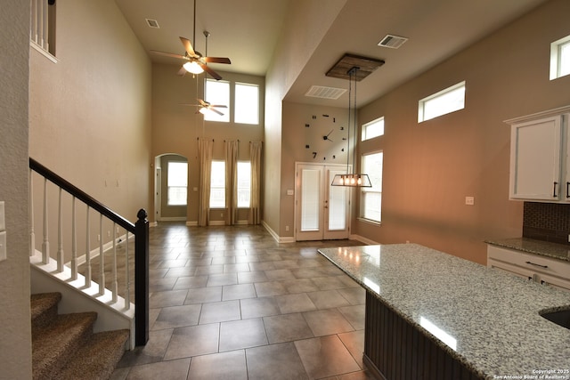 entrance foyer featuring tile patterned flooring, stairway, a ceiling fan, and visible vents