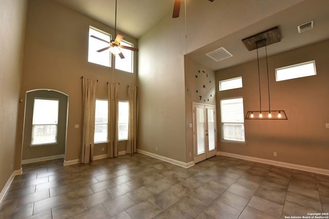 tiled entrance foyer with arched walkways, a high ceiling, visible vents, and a ceiling fan