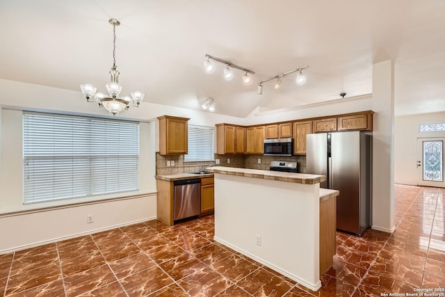 kitchen featuring a kitchen island, vaulted ceiling, hanging light fixtures, appliances with stainless steel finishes, and tasteful backsplash