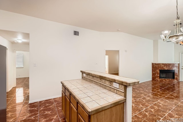 kitchen with tile counters, pendant lighting, visible vents, and marble finish floor