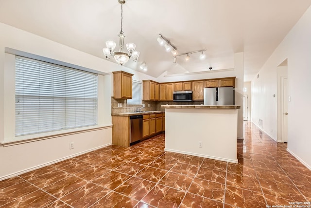 kitchen featuring tasteful backsplash, lofted ceiling, a kitchen island, appliances with stainless steel finishes, and decorative light fixtures