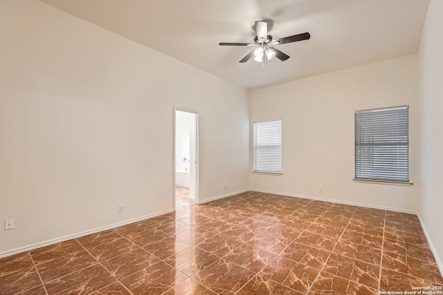 empty room with marble finish floor, a ceiling fan, and baseboards