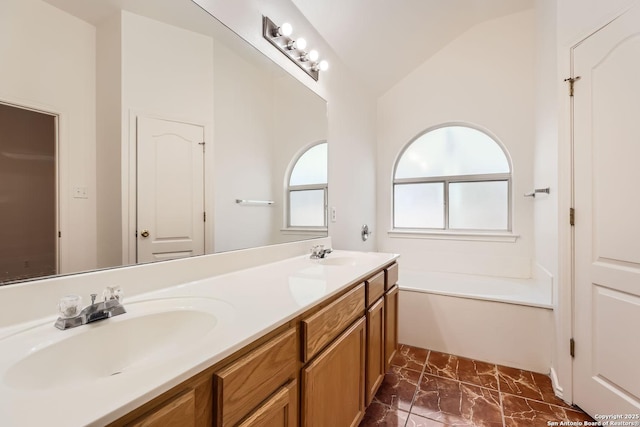 bathroom featuring lofted ceiling, a garden tub, double vanity, and a sink