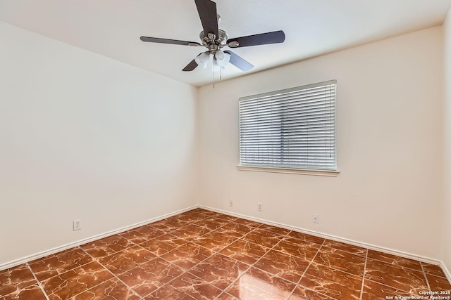 spare room featuring a ceiling fan and baseboards