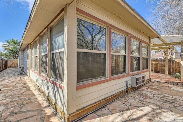 view of side of home featuring a wall mounted AC, fence, and a patio