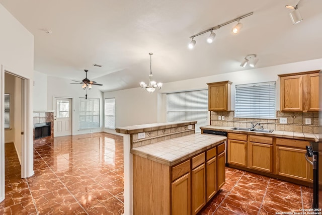 kitchen with pendant lighting, tile countertops, stainless steel range oven, a kitchen island, and a sink