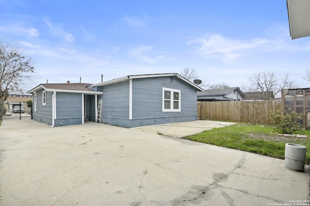 back of house featuring driveway, fence, and a patio