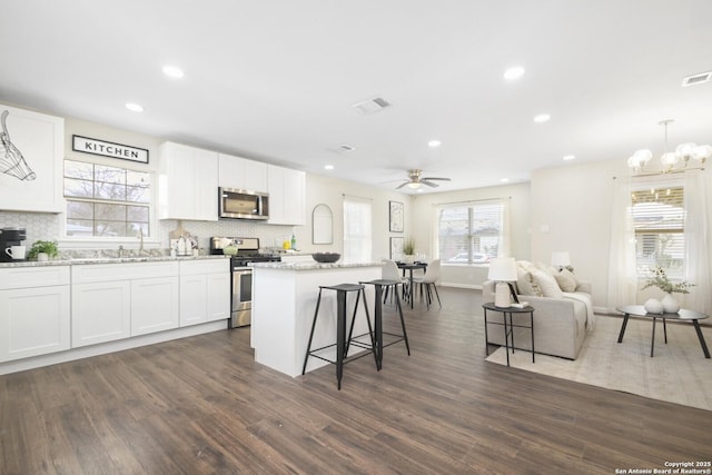 kitchen with visible vents, appliances with stainless steel finishes, a center island, hanging light fixtures, and white cabinetry