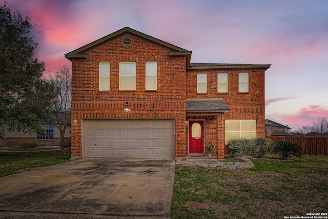 traditional-style home featuring brick siding, an attached garage, a front yard, fence, and driveway