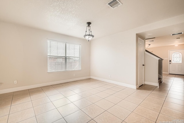 unfurnished room with a textured ceiling, light tile patterned floors, plenty of natural light, and visible vents