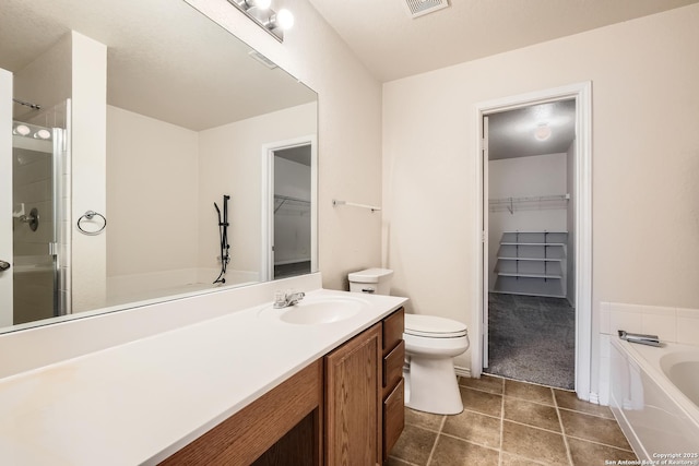 bathroom with a spacious closet, toilet, vanity, a shower stall, and a bath