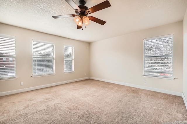 spare room with light carpet, baseboards, and a textured ceiling