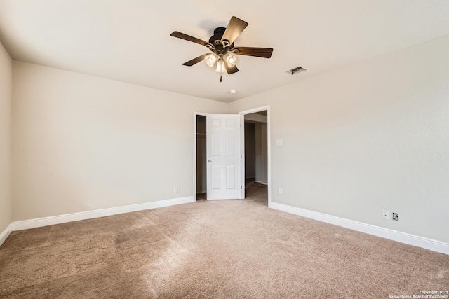 carpeted spare room with ceiling fan, visible vents, and baseboards