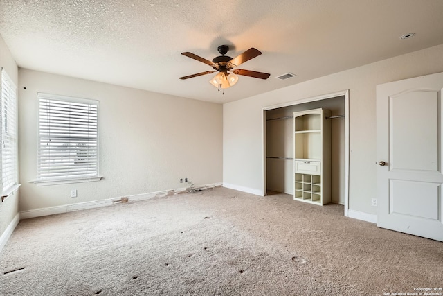 unfurnished bedroom with a textured ceiling, a closet, carpet flooring, and visible vents