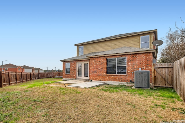 back of house featuring a yard, a fenced backyard, cooling unit, and brick siding