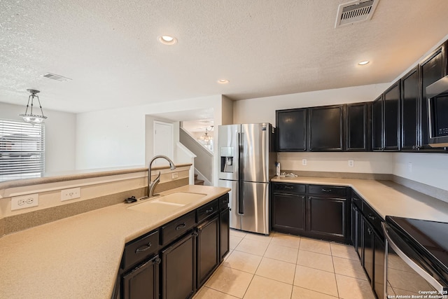 kitchen featuring visible vents, hanging light fixtures, light countertops, stainless steel refrigerator with ice dispenser, and a sink