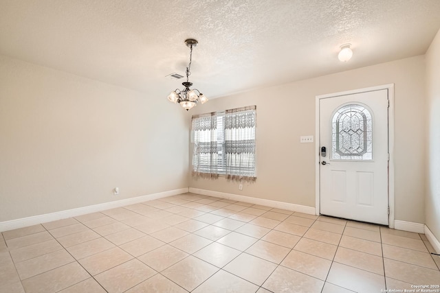 foyer entrance featuring baseboards, visible vents, a textured ceiling, a notable chandelier, and light tile patterned flooring