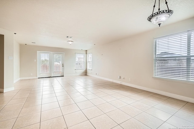 spare room featuring visible vents, a textured ceiling, baseboards, and light tile patterned floors