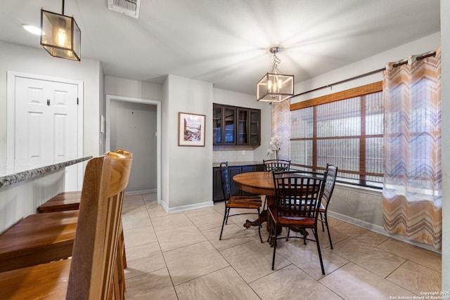 dining space with light tile patterned floors, baseboards, visible vents, and a chandelier