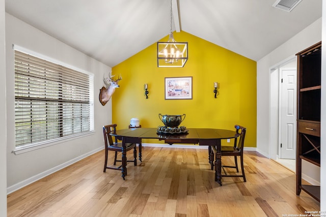 dining space featuring a notable chandelier, visible vents, vaulted ceiling, and wood finished floors