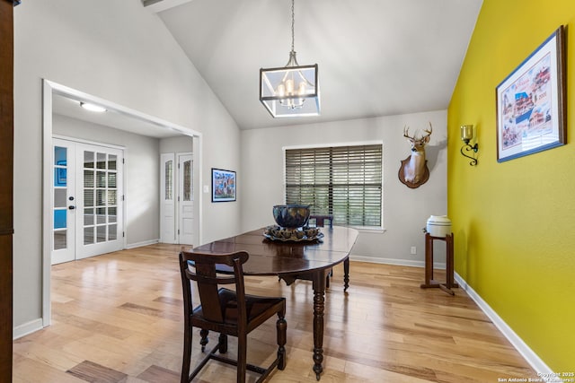 dining room with french doors, a notable chandelier, light wood finished floors, vaulted ceiling, and baseboards