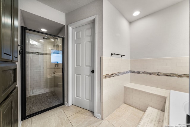 full bathroom with tile walls and a shower stall