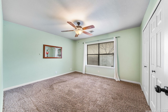 unfurnished bedroom with baseboards, visible vents, a textured ceiling, carpet flooring, and a closet