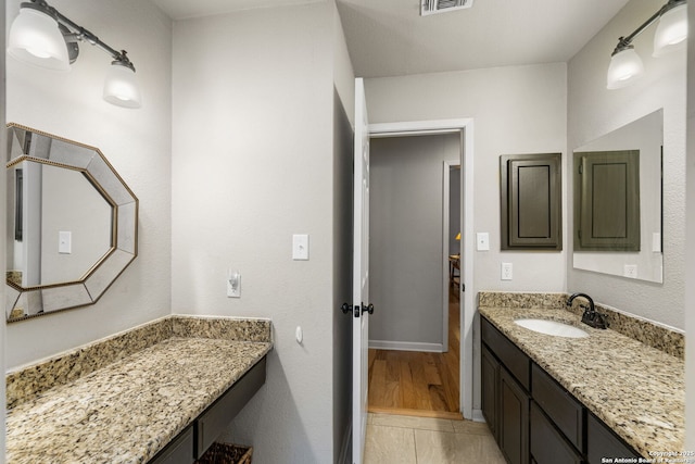 bathroom featuring visible vents, wood finished floors, vanity, and baseboards