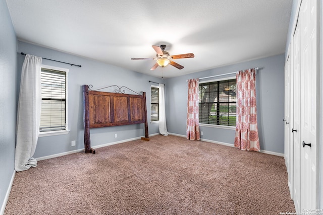 unfurnished bedroom featuring carpet floors, baseboards, and a ceiling fan