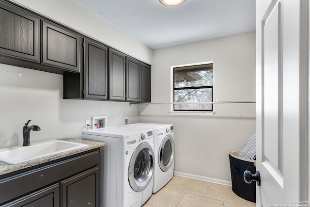 laundry area with washer and clothes dryer, light tile patterned floors, cabinet space, a sink, and baseboards