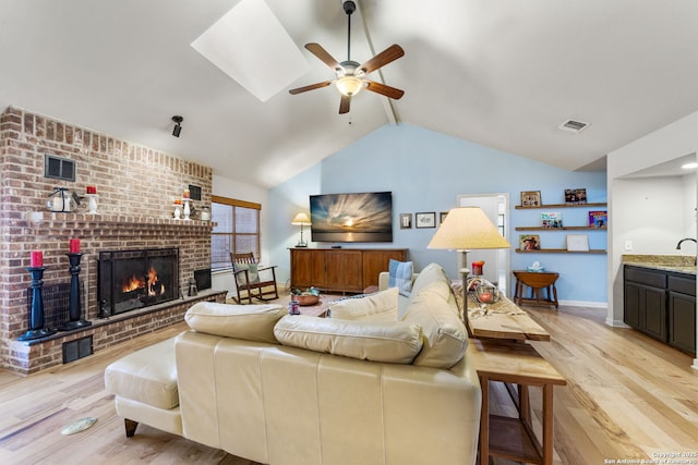 living area featuring a fireplace, visible vents, and light wood-style floors