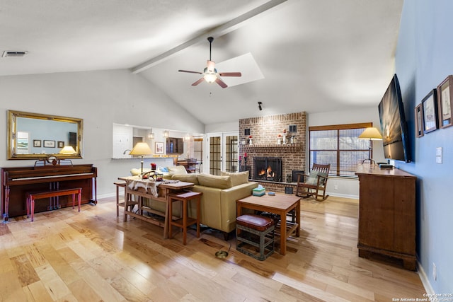 living area with light wood-style floors, a brick fireplace, visible vents, and beamed ceiling