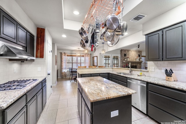 kitchen with visible vents, a kitchen island, a peninsula, stainless steel appliances, and a sink