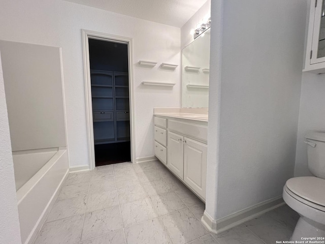 bathroom featuring toilet, marble finish floor, baseboards, and a walk in closet