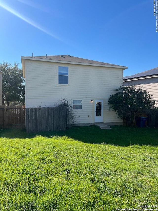 view of side of home featuring fence and a lawn