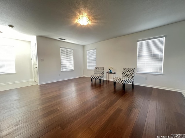 unfurnished room with baseboards, visible vents, dark wood finished floors, and a textured ceiling