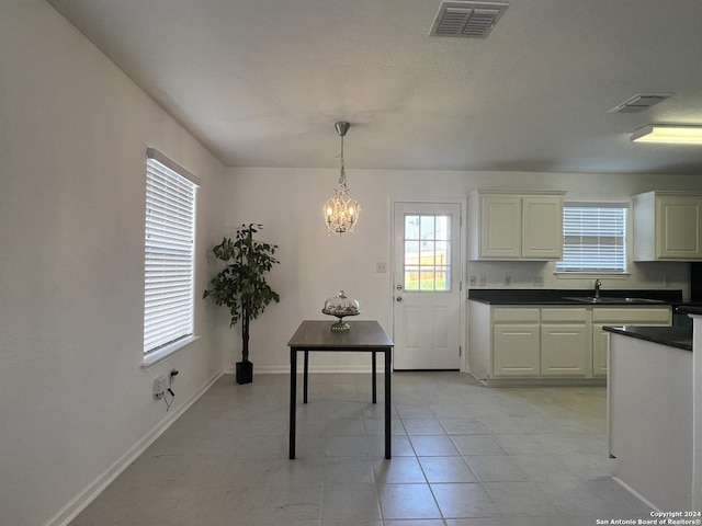 kitchen featuring dark countertops, a sink, visible vents, and pendant lighting