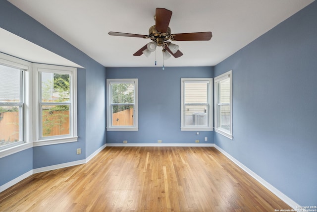 spare room featuring light wood-type flooring, ceiling fan, and baseboards