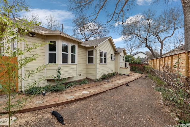 view of home's exterior with crawl space and fence