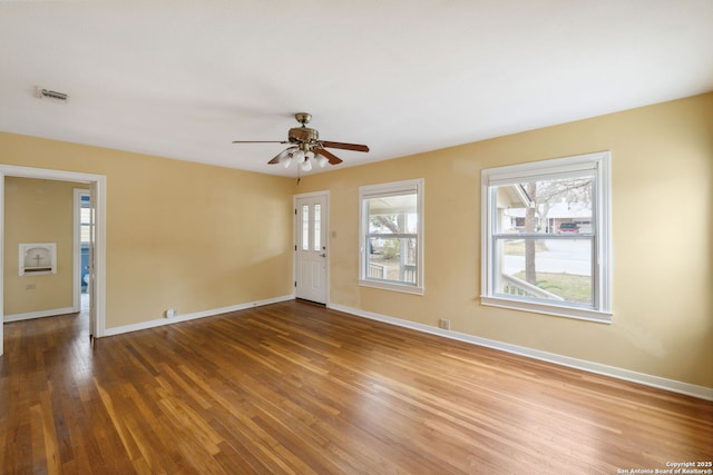 spare room with baseboards, visible vents, ceiling fan, and wood finished floors