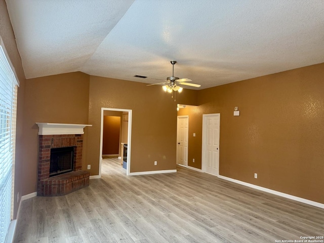 unfurnished living room with lofted ceiling, a ceiling fan, baseboards, light wood-style floors, and a brick fireplace