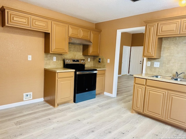 kitchen featuring tasteful backsplash, light countertops, stainless steel range with electric cooktop, under cabinet range hood, and a sink